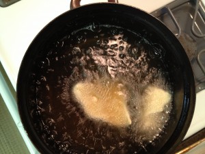 dough is frying in a pot of hot oil