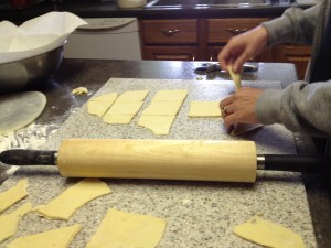 a large rolling pin is used in this picture which shows the Roll Kuchen dough rolled out and cut into pieces