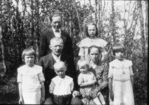 family portrait of mother, father, and six children in front of trees