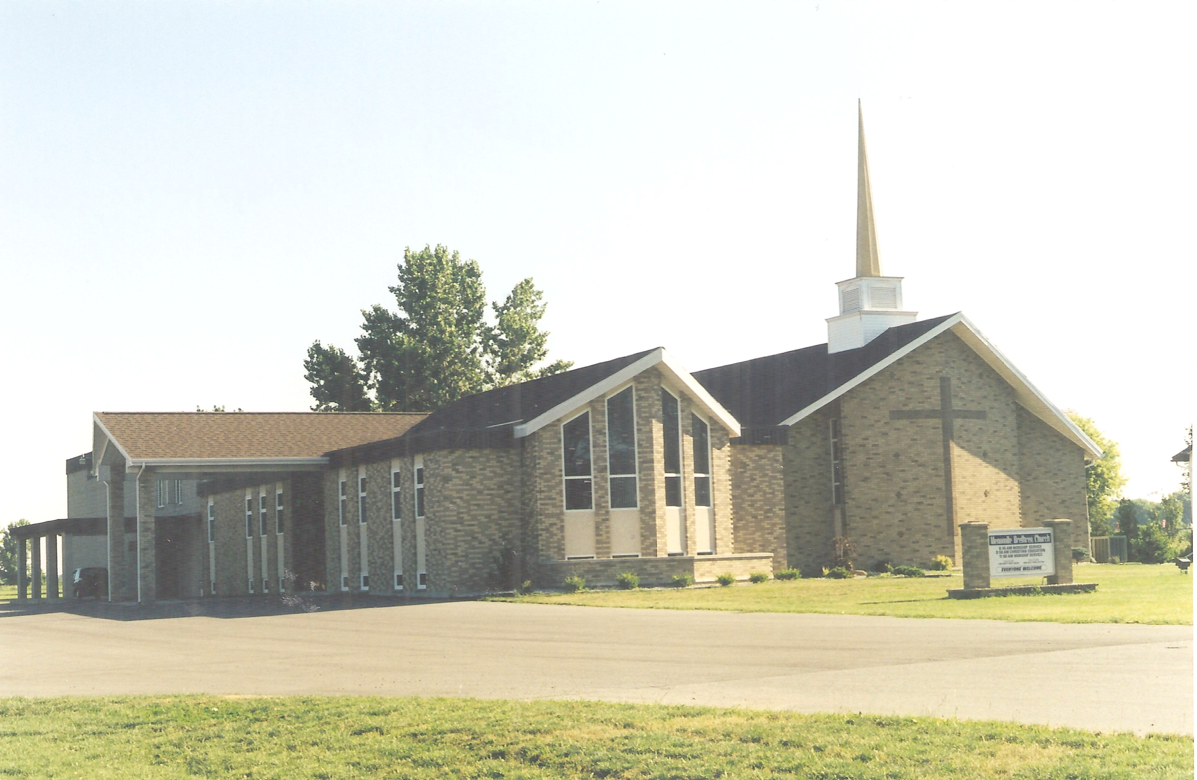 Large yellow brick church with a white steeple