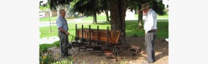 Two men with farm equipment under a tree