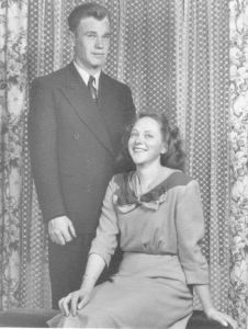 portrait of young man standing behind a young woman who is sitting